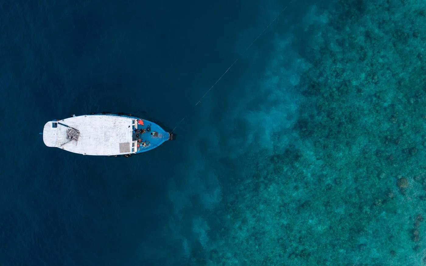 A boat photographed from directly above over a reef