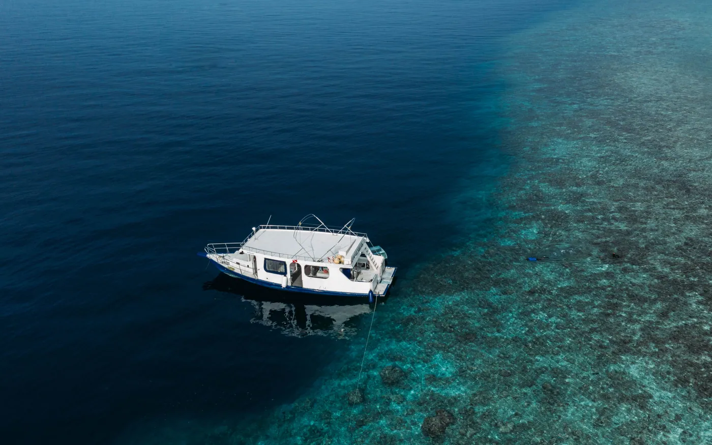 A small boat moored above a shallow reef in clear water
