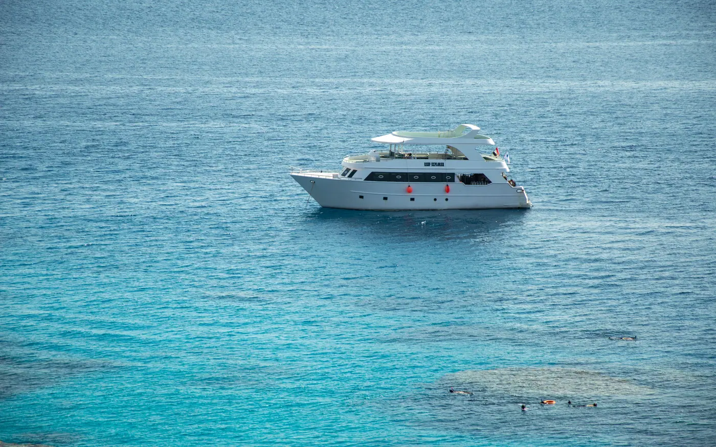 A boat lying over clear shallow water beside a reef