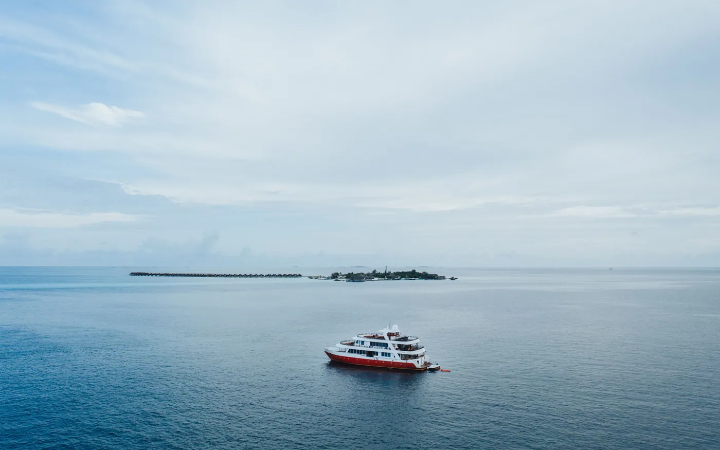 A boat riding at anchor on calm water under high cloud