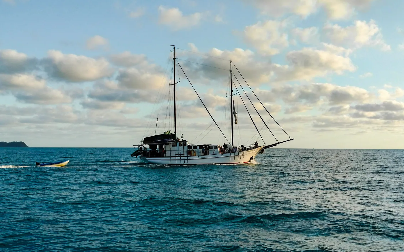 A boat lying off a reef with a tender alongside