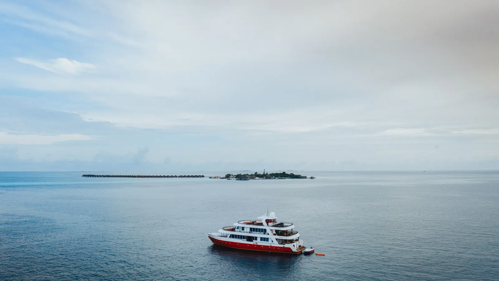 A dive boat lying at anchor beside a low island