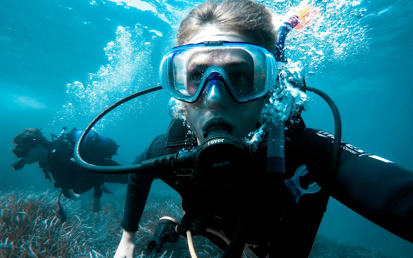 A scuba diver just below the surface with the regulator in and mask on