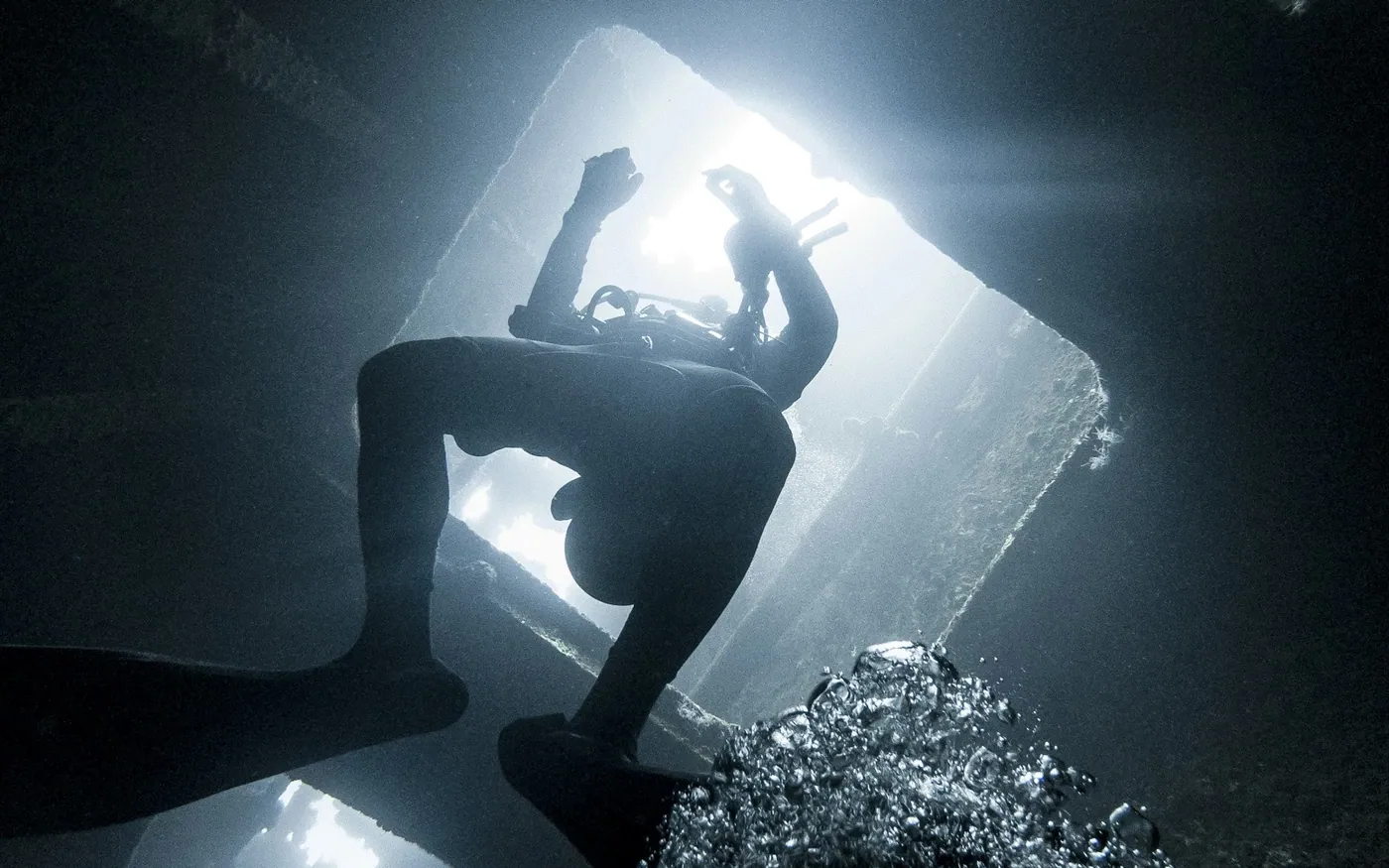 A scuba diver silhouetted in an opening in a wreck