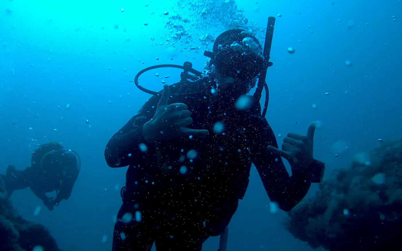 A scuba diver in blue water with a second diver visible behind
