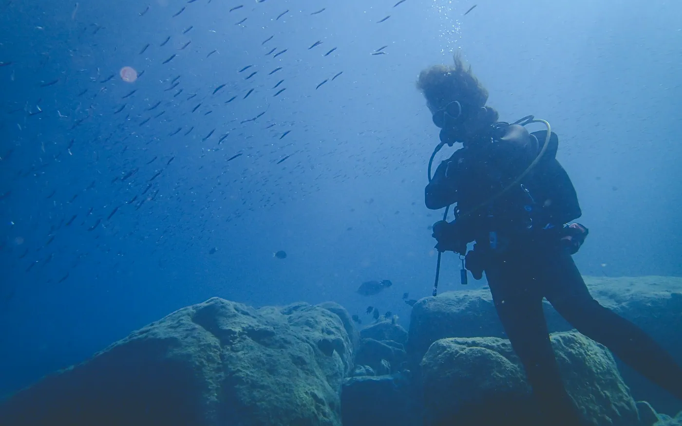 A scuba diver holding position beside large boulders