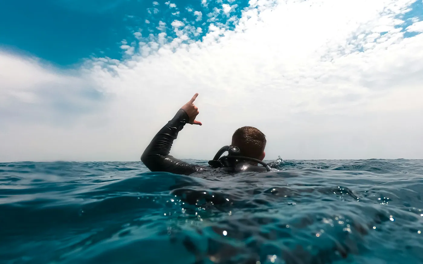 A diver at the surface raising one arm clear of the water
