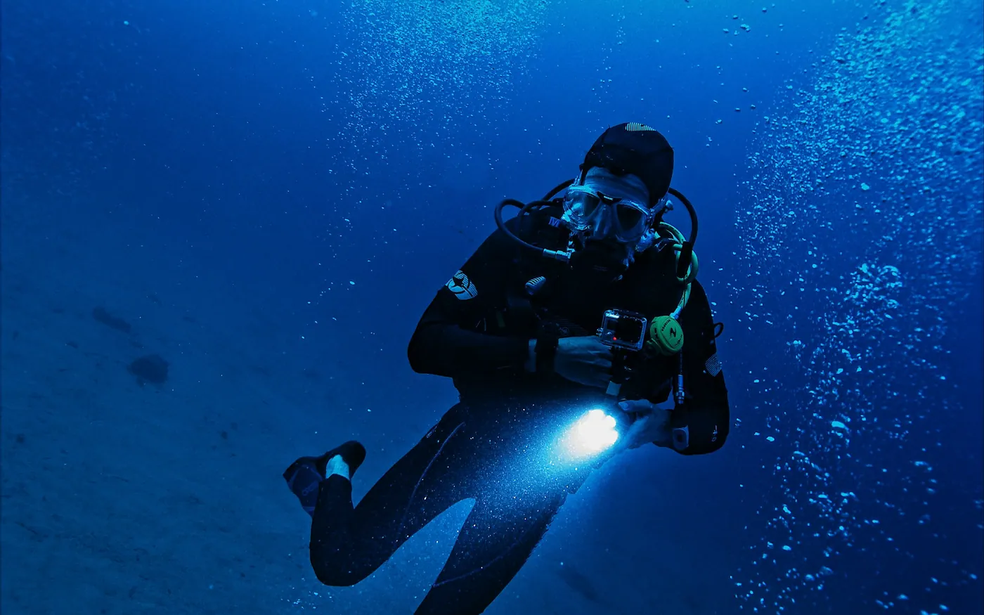 A scuba diver carrying a lit torch in deep blue water