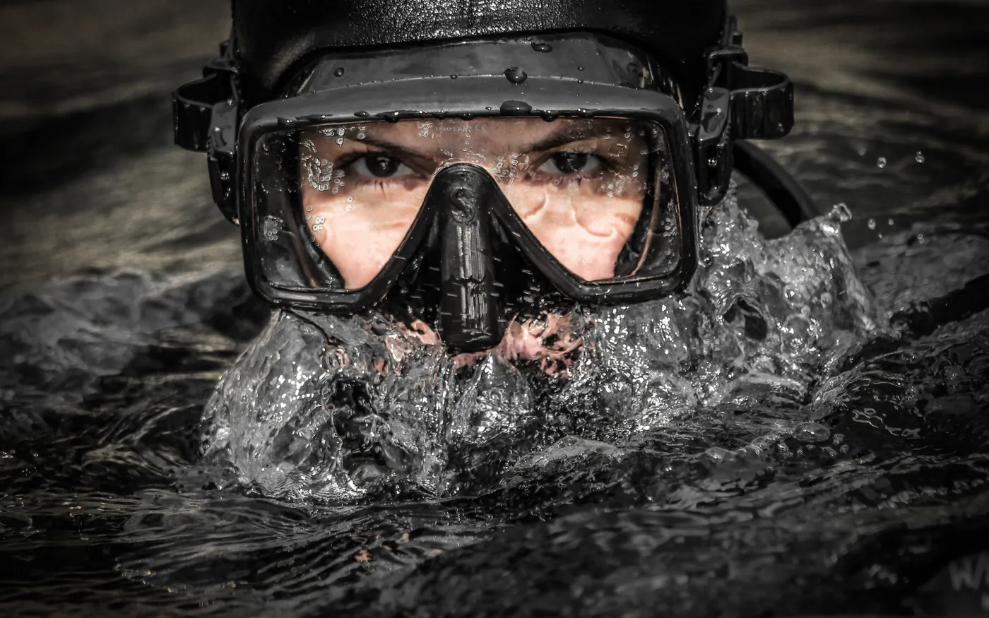 A diver at the surface wearing a mask, water running off the hood