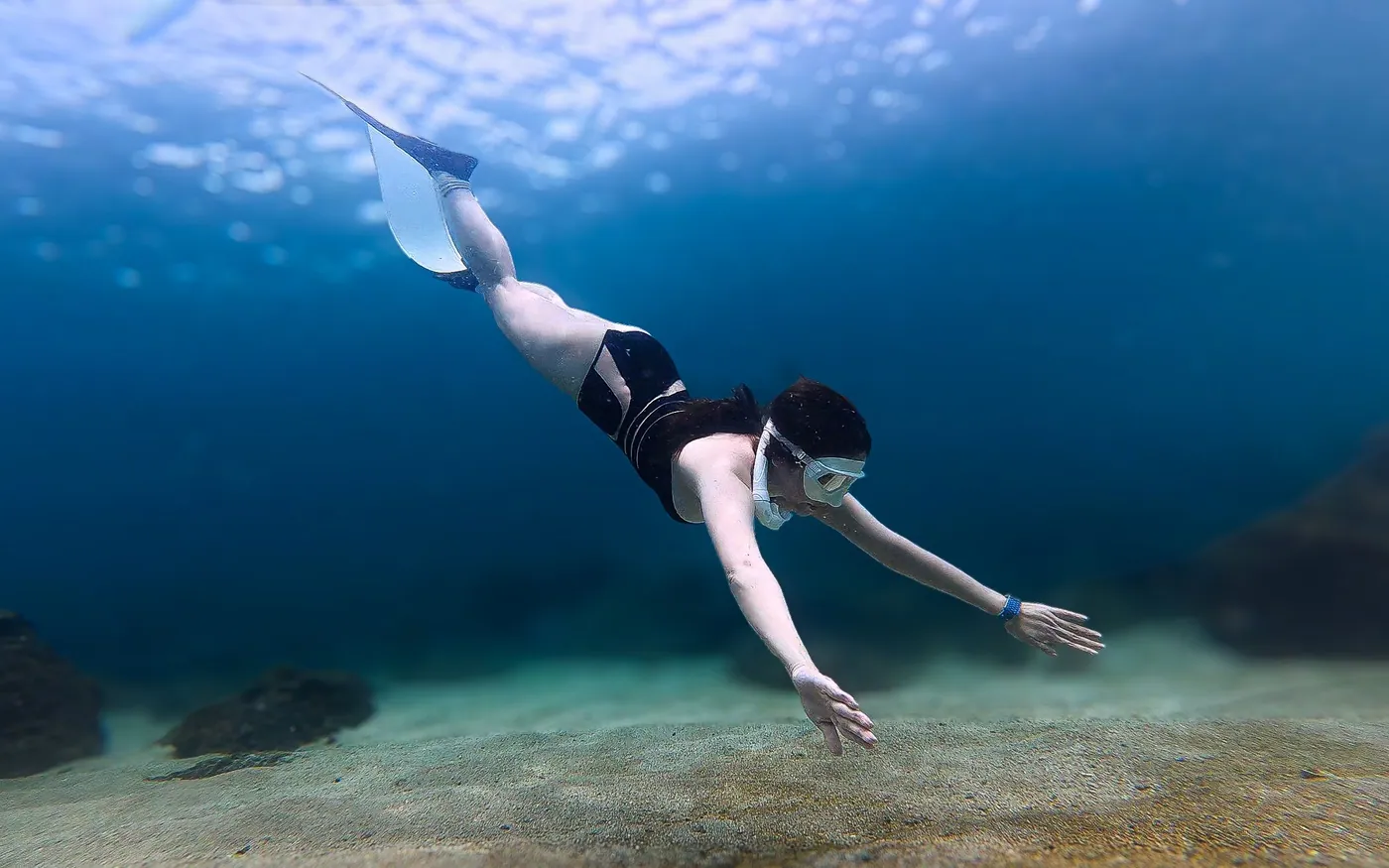A snorkeler swimming above a shallow sandy bottom