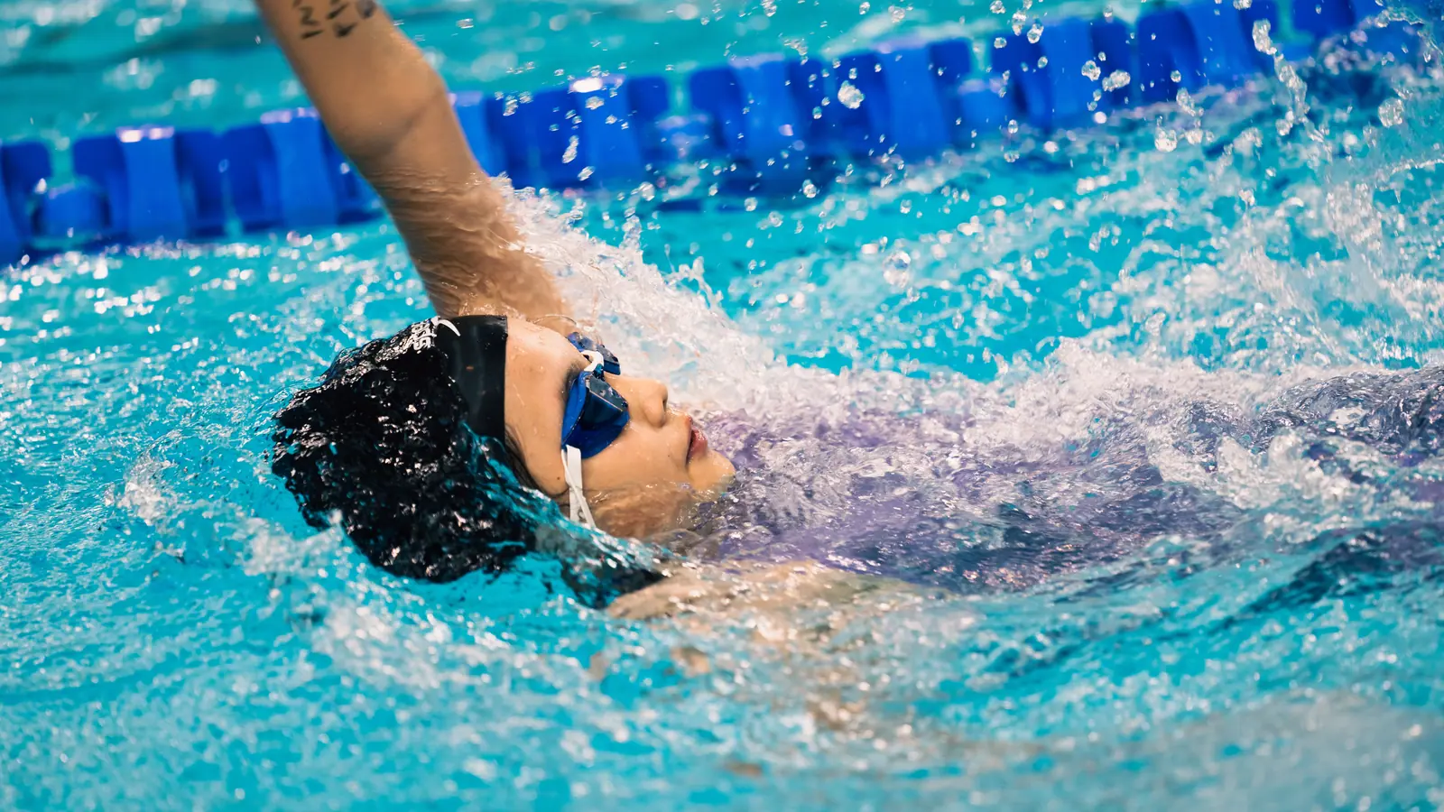 A swimmer taking a breath mid front crawl in a pool lane