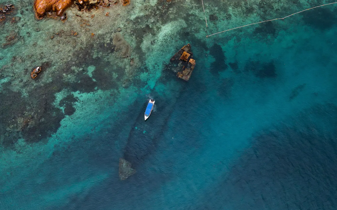 A boat moored above a submerged wreck seen from the air