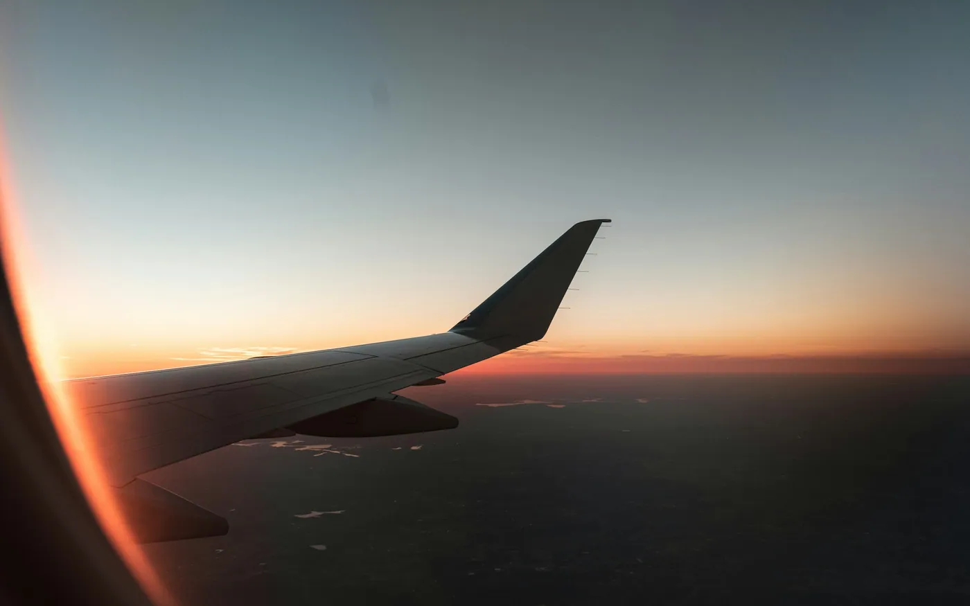 An aircraft wing against a sunset at cruising altitude