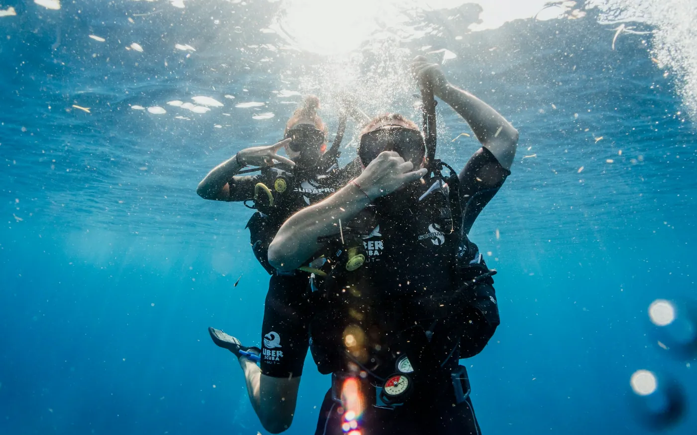 Two scuba divers close together near the surface, one supporting the other