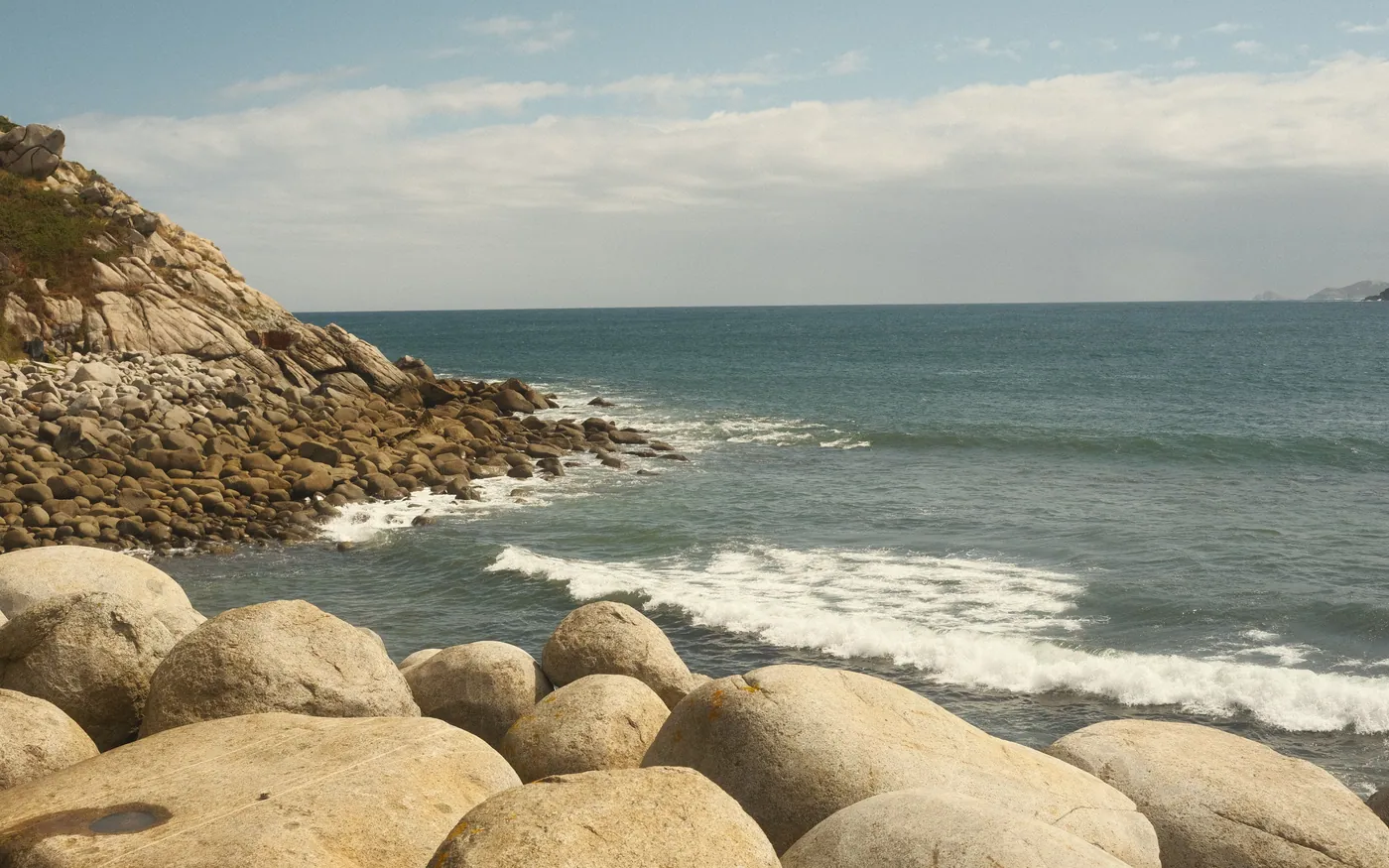 A boulder-strewn beach with surf, typical of Cape Ann shore entries