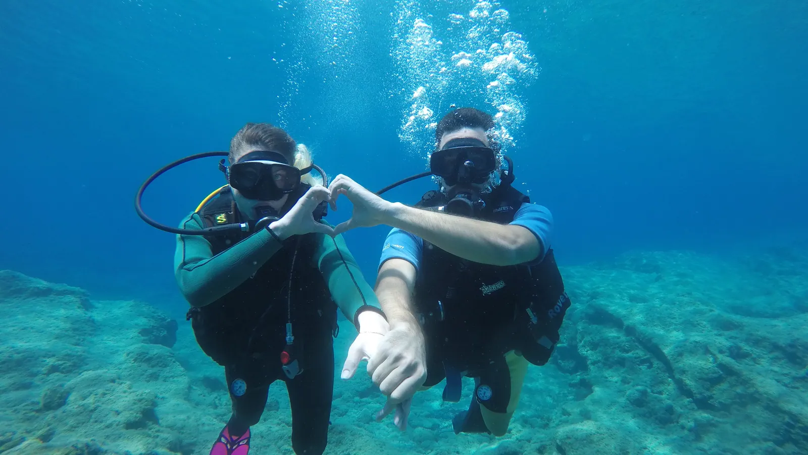 Two scuba divers side by side making a signal together underwater