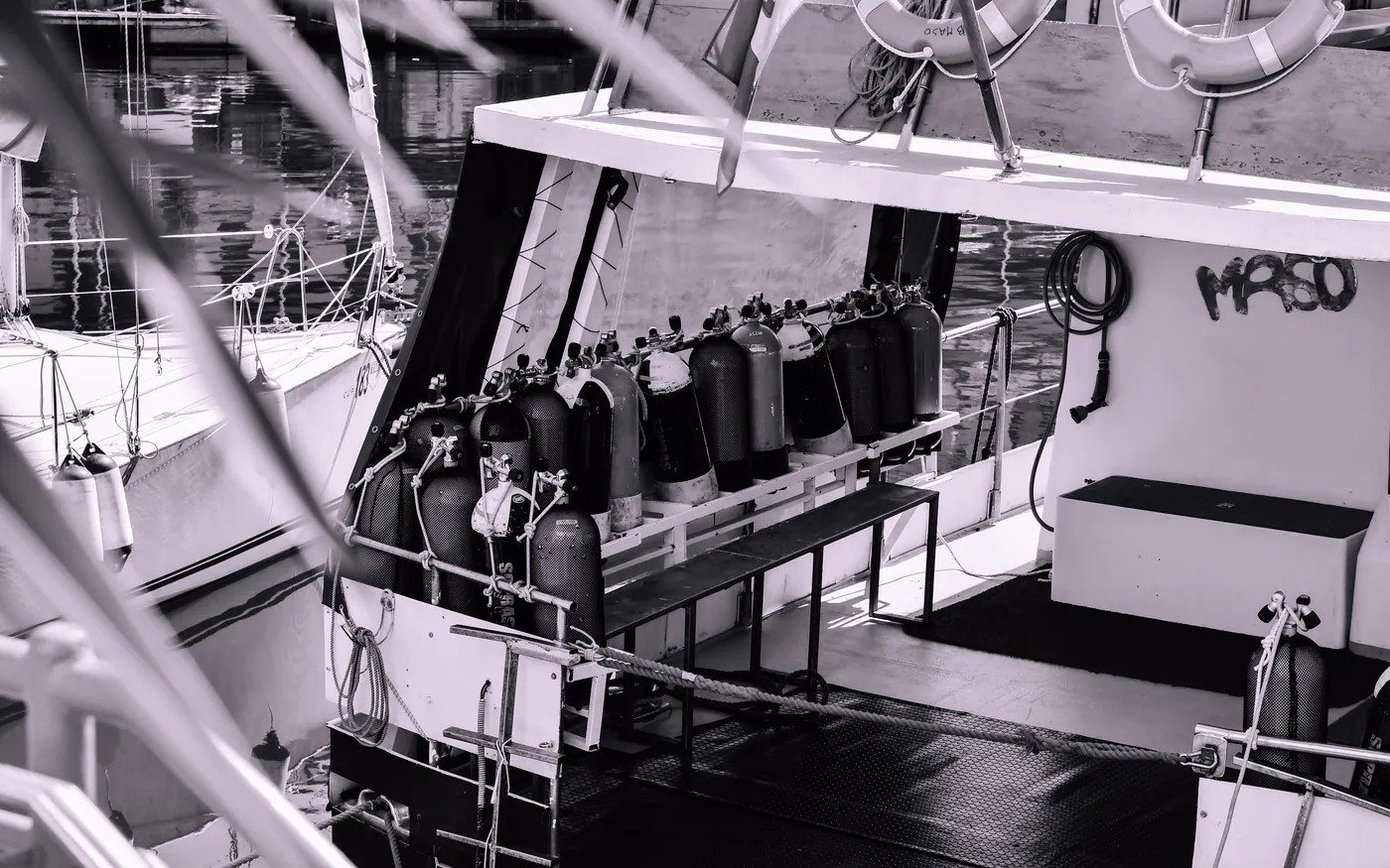 Scuba cylinders racked in a bench along the deck of a dive boat