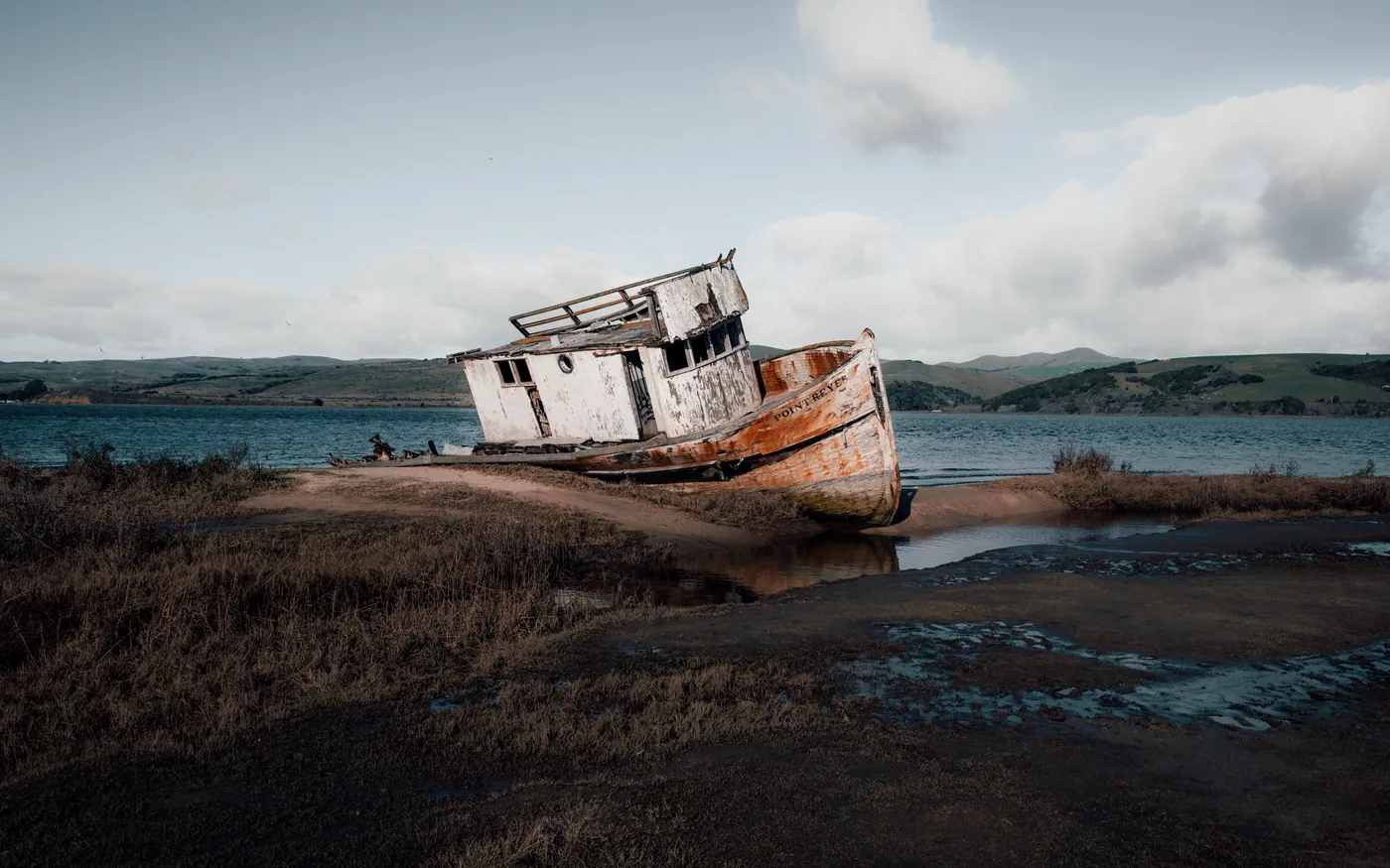 A derelict wooden boat abandoned on a shoreline