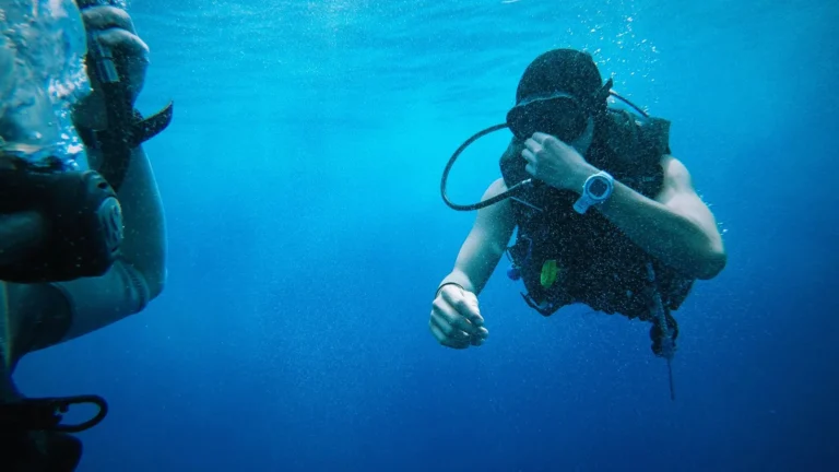 One scuba diver swimming toward another to offer assistance