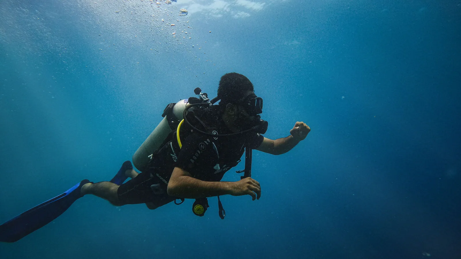 A scuba diver ascending slowly through blue water