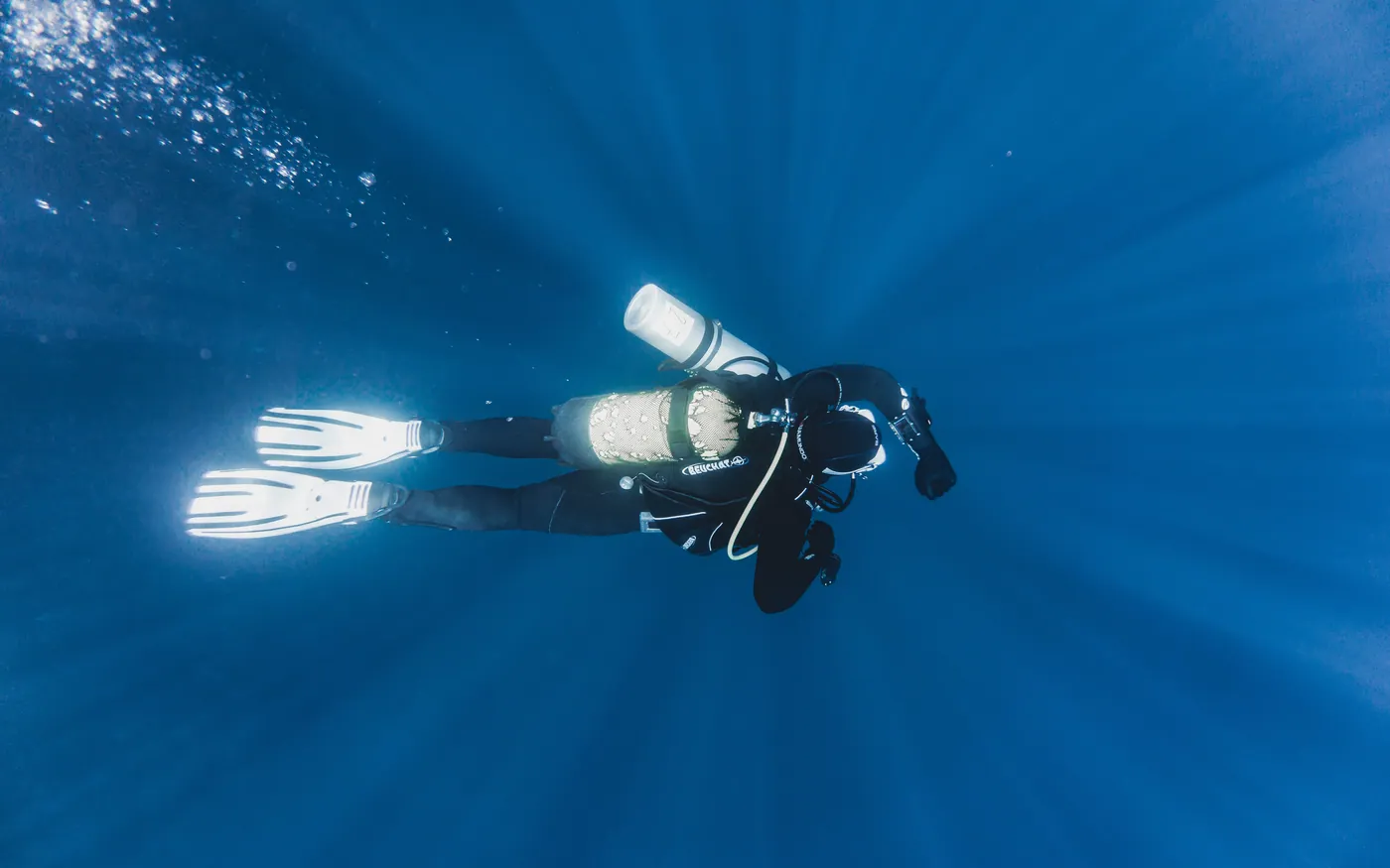 A scuba diver seen from below against a bright surface