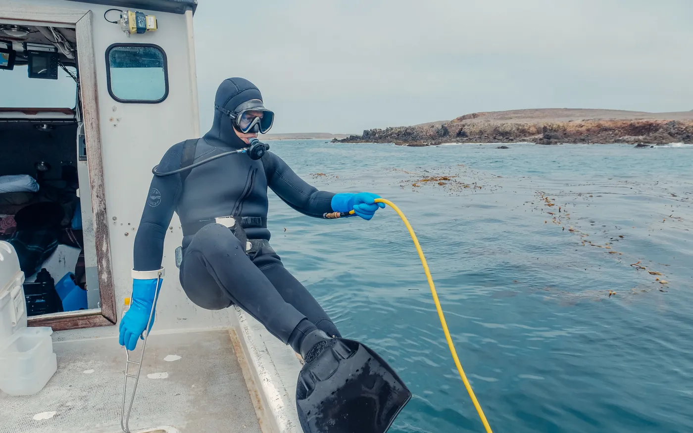 A diver in full scuba gear on the deck of a boat, ready to enter the water