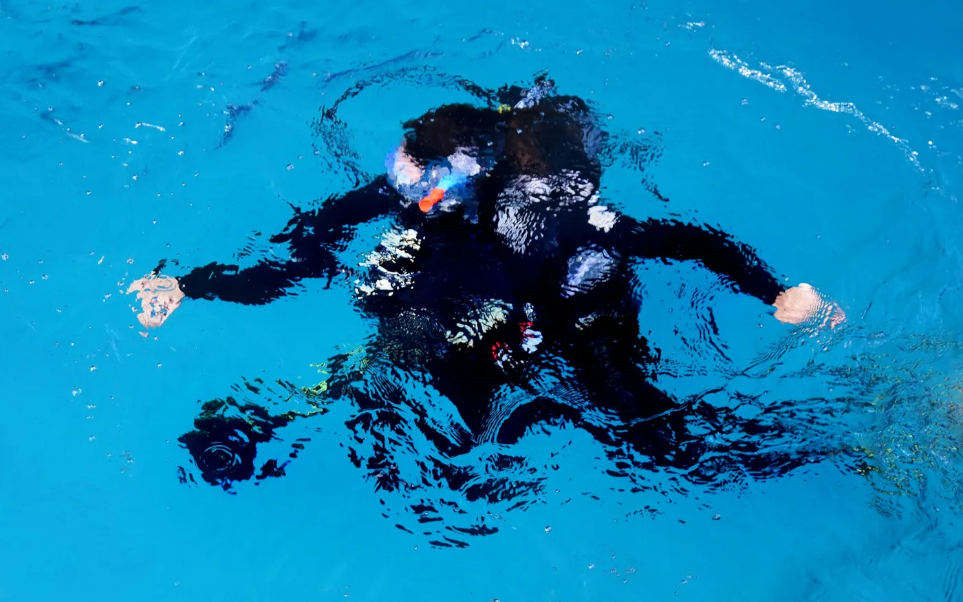 A scuba diver floating face-up at the surface in open water