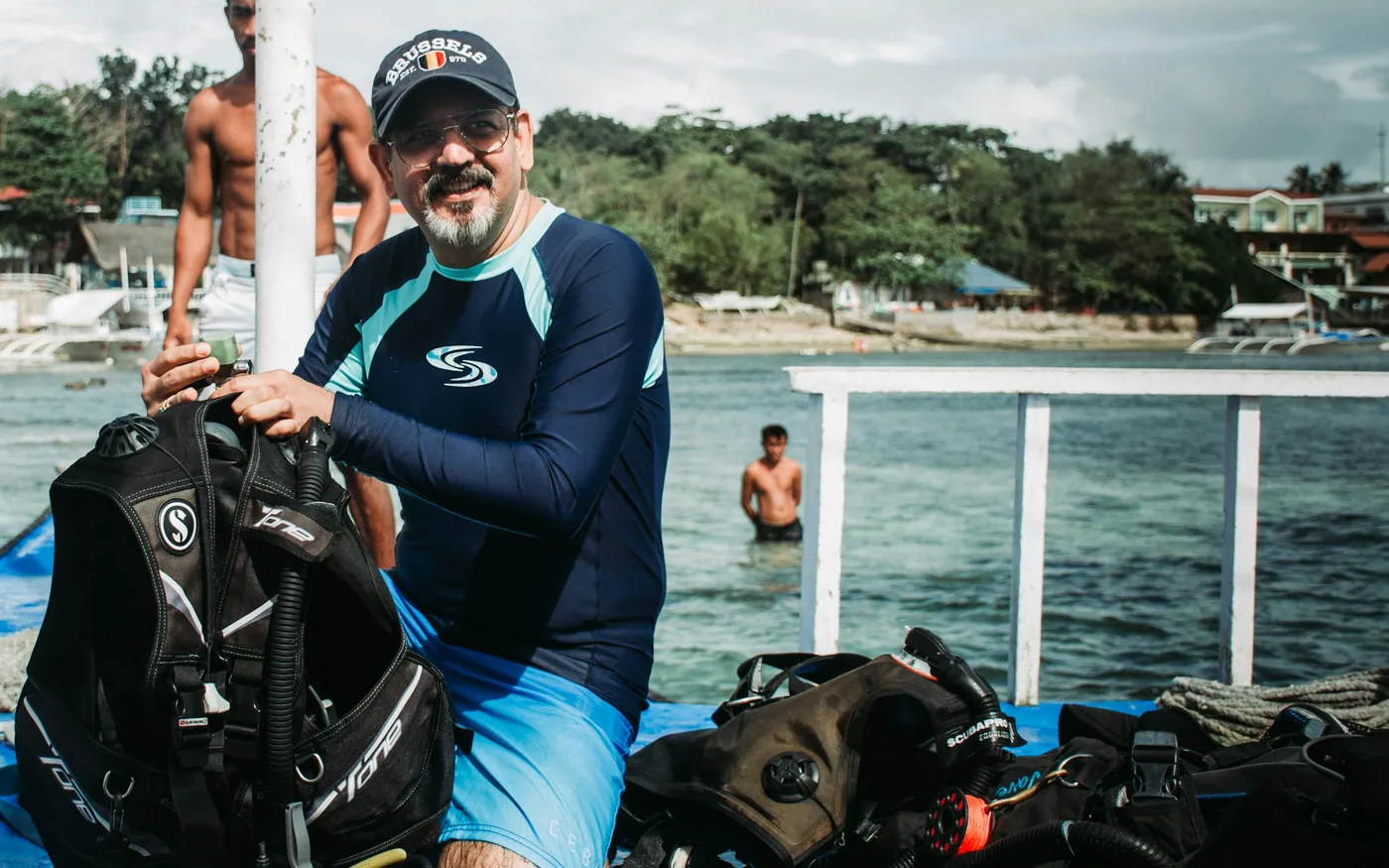 A diver holding a BCD with more equipment laid out beside him