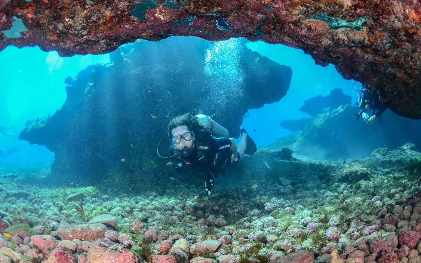 A scuba diver passing through an archway in a reef
