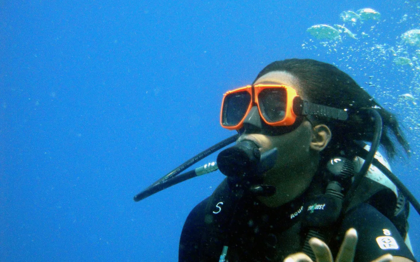 Close-up of a scuba diver in an orange mask breathing from a regulator
