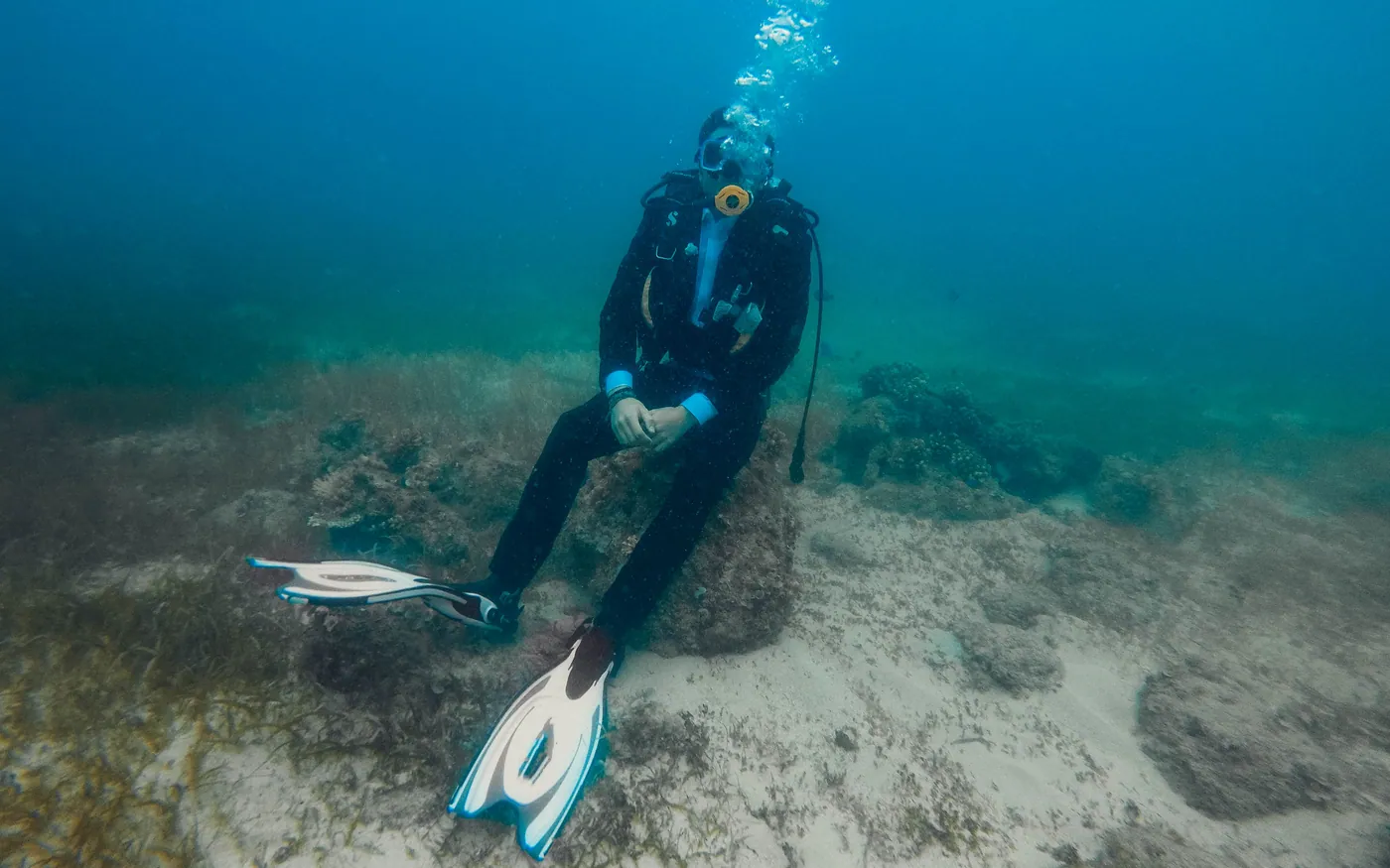 A scuba diver resting on the seabed rather than hovering above it