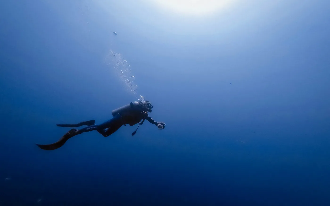 A scuba diver moving slowly through open blue water
