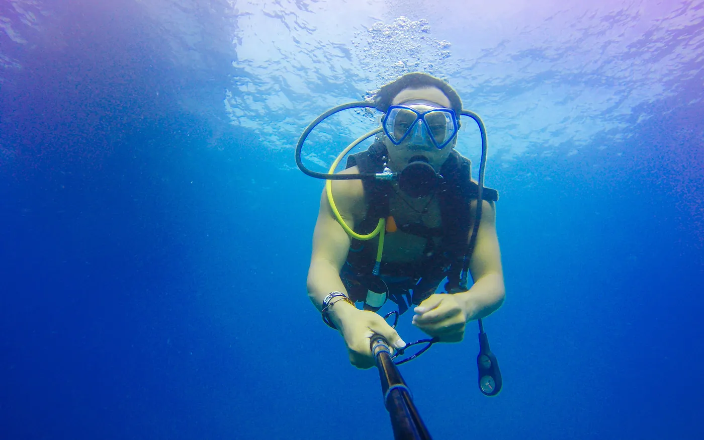 A scuba diver near the surface holding the inflator hose