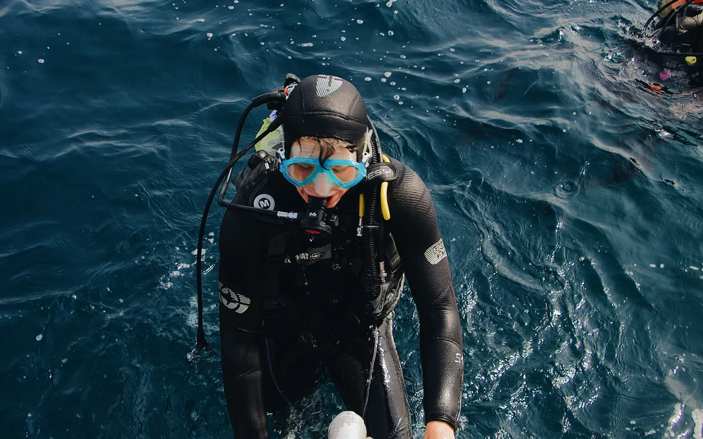 A scuba diver climbing the ladder back onto a boat after an ocean dive