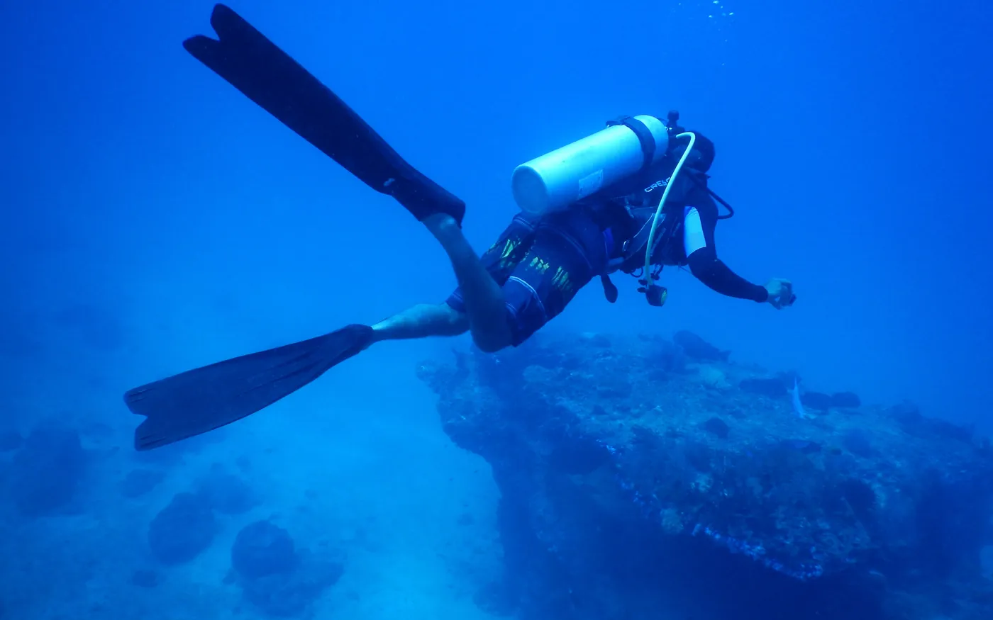 A scuba diver swimming above the seabed in blue water