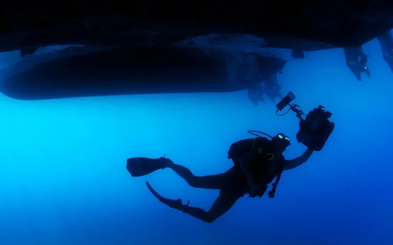 A scuba diver silhouetted in open blue water
