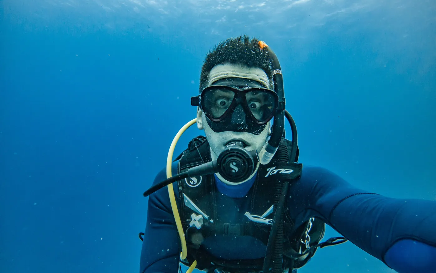 A scuba diver underwater wearing a mask and breathing from a regulator