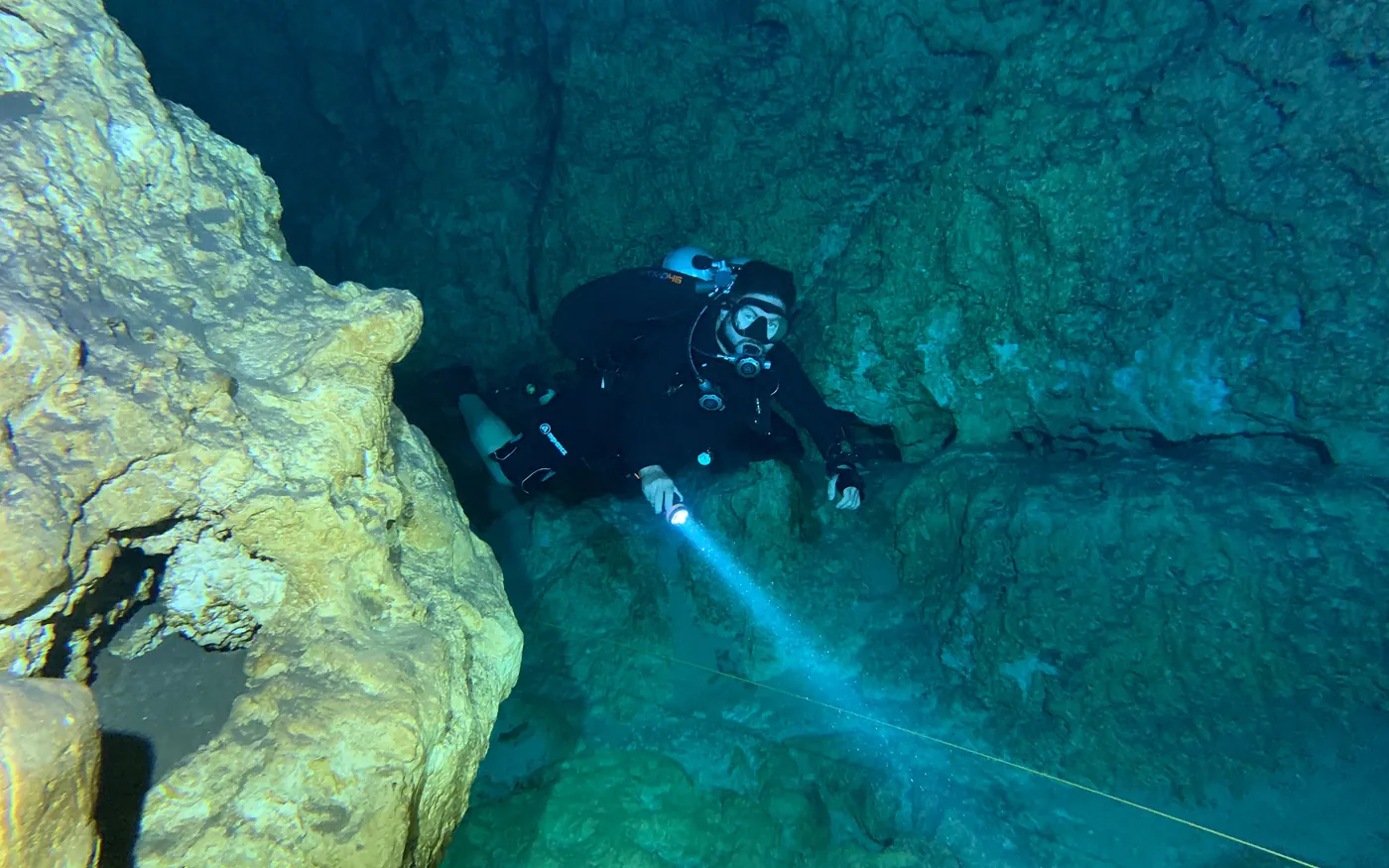 A scuba diver using a dive light among submerged rock formations
