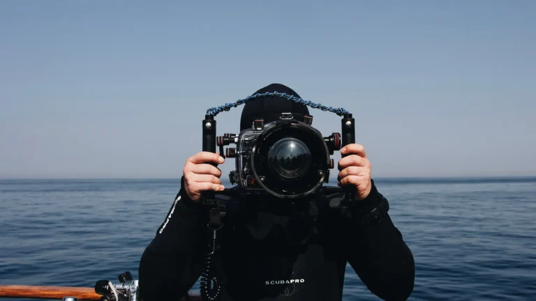 A diver holding an underwater camera in its housing before a dive