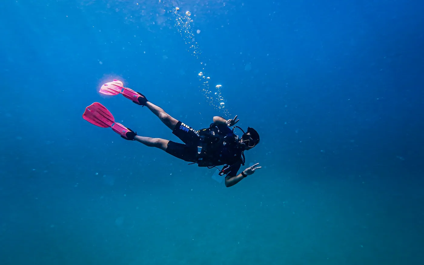 A scuba diver with bright fins swimming in open blue water