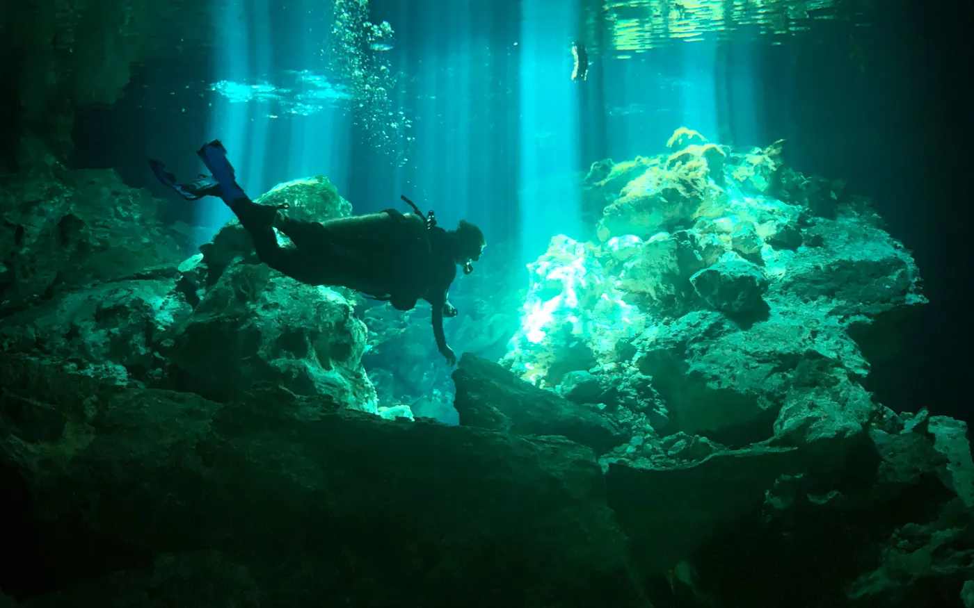 Two scuba divers in green water with light beams cutting through