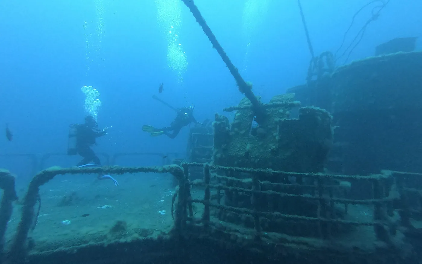 Two scuba divers exploring a wreck well below the surface light