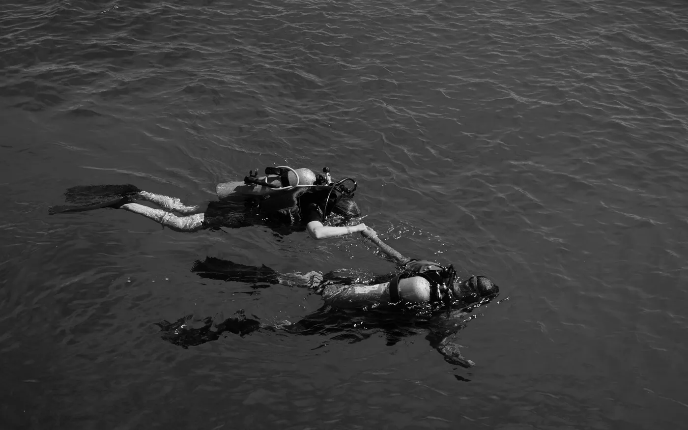 Two divers at the surface in flat grey water waiting for pickup