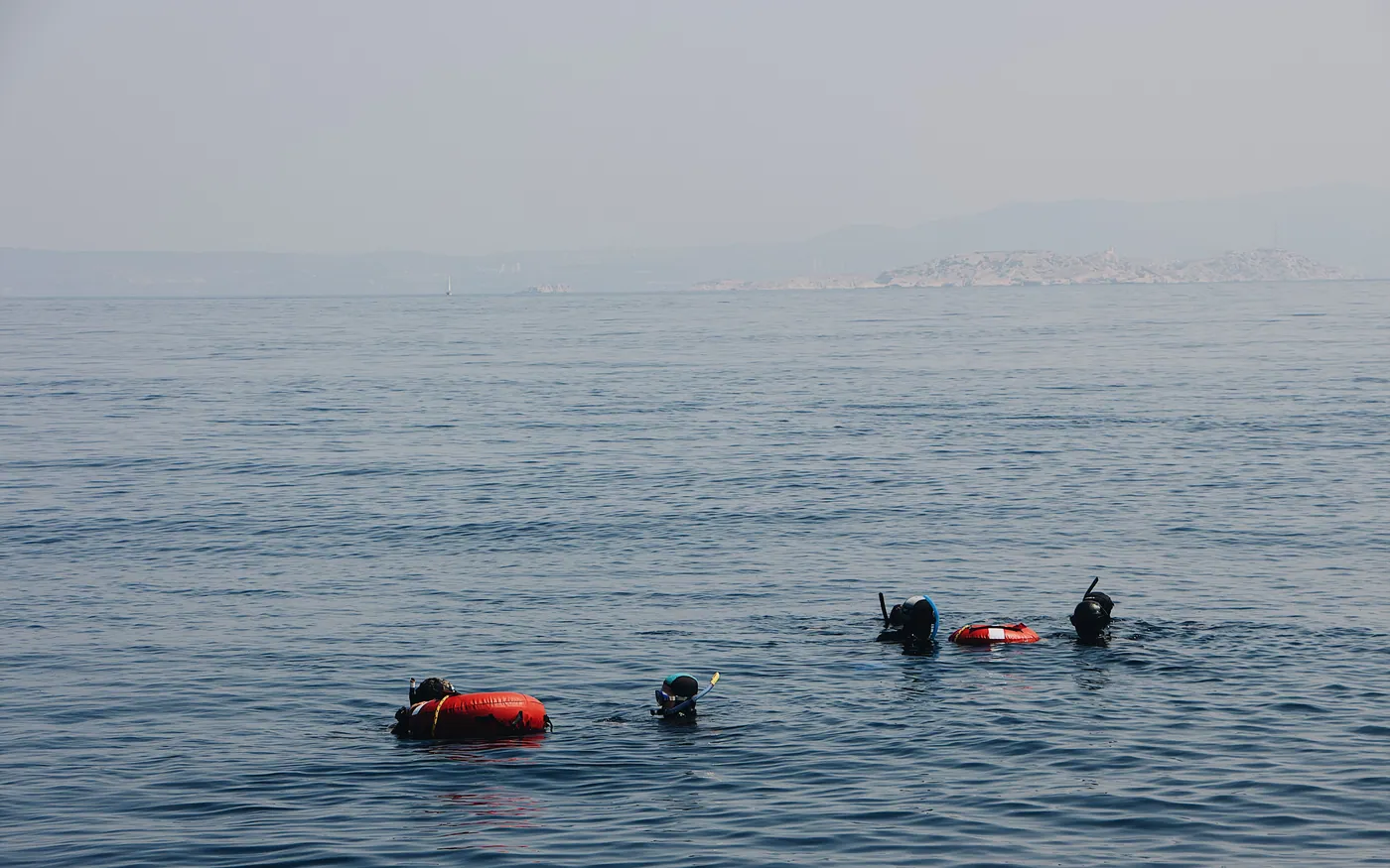 Divers waiting at the surface in grey water with surface floats