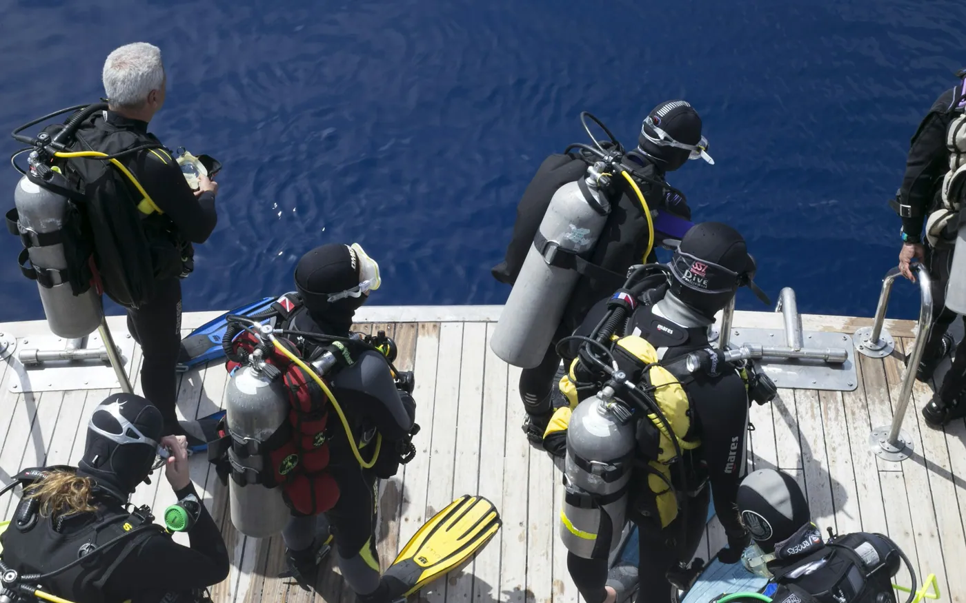 Divers with assembled cylinders and BCDs on a boat deck