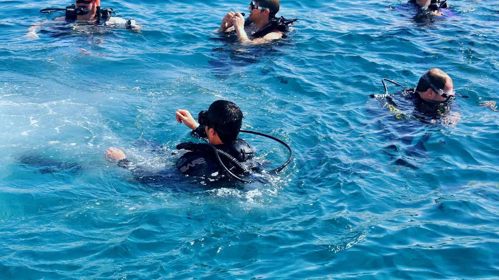 A group of scuba divers together at the surface with an instructor talking to them