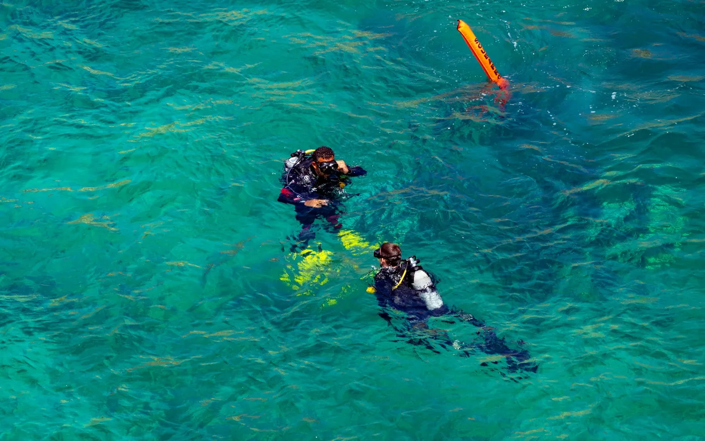 Two divers at the surface beside an inflated marker