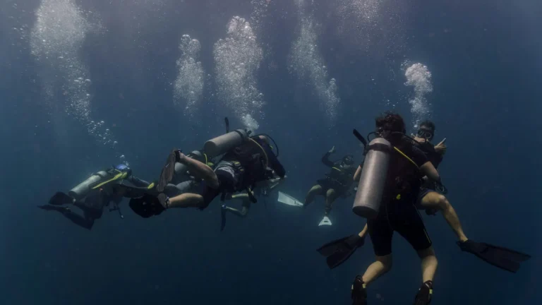 Three scuba divers grouped together in dim open water