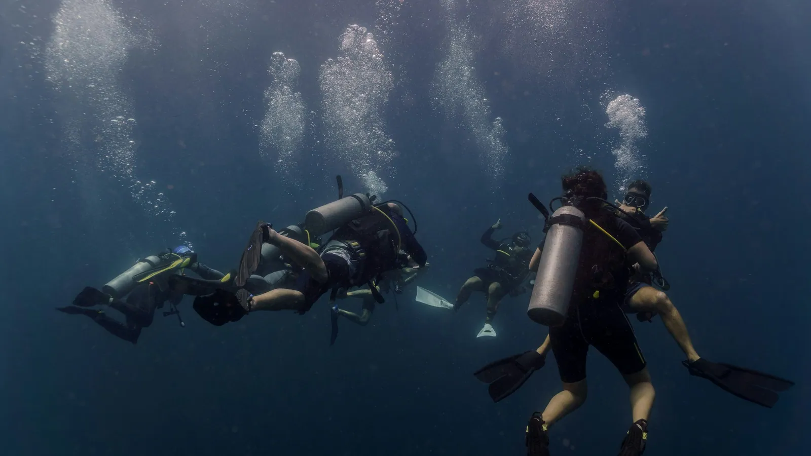 Three scuba divers grouped together in dim open water