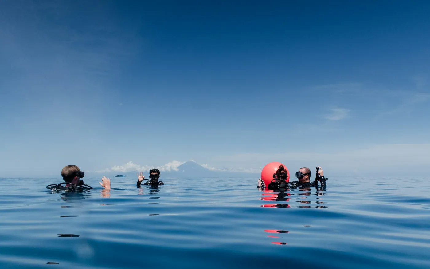 Several divers floating together at the surface on flat calm water